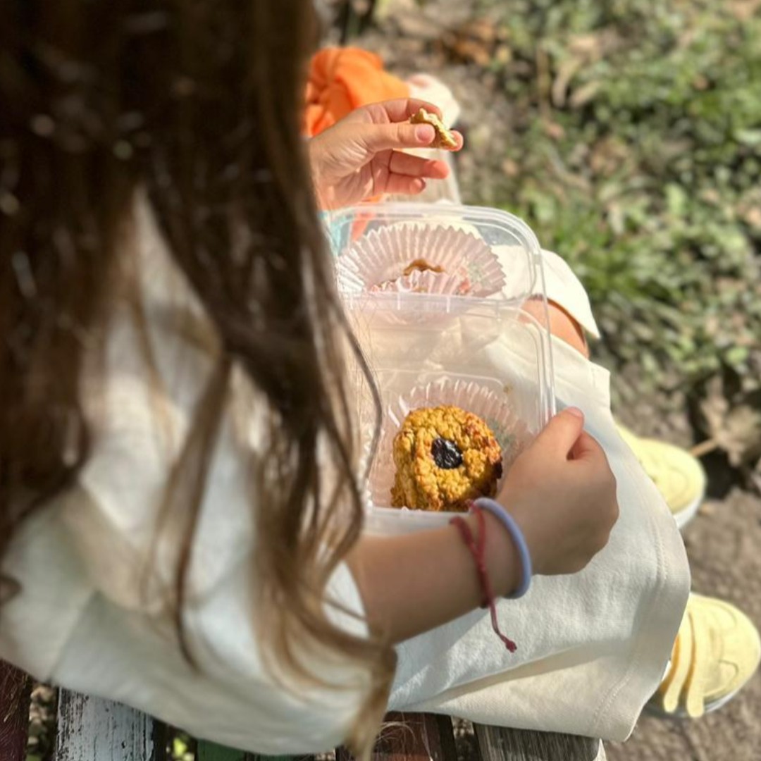 fetita in parc cu rochie galbena, toamna, care tine in mana pachetelul cu fursecuri cu dovleac aurii. mananca cu pofta dintr-un fursec sanatos, fara zahar, care are merisoare